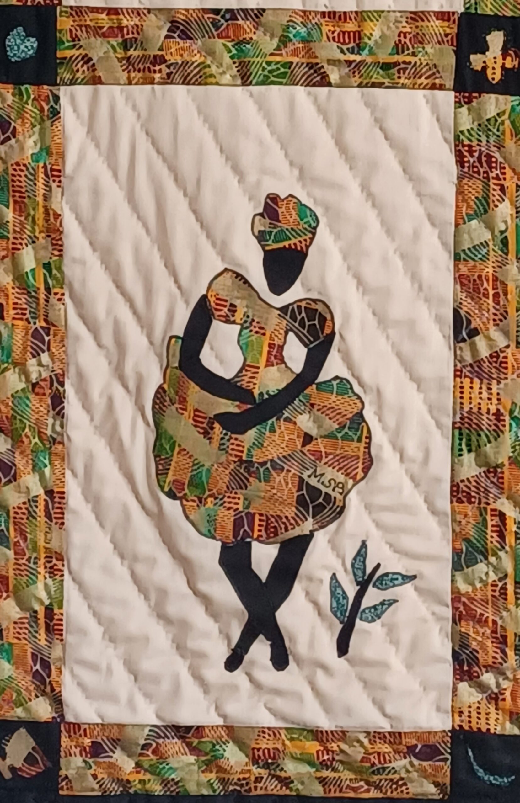 A quilted textile art piece featuring a silhouette of a poised African woman dressed in vibrant Ankara fabric, adorned with intricate patterns, set against a quilted white background with a decorative border.