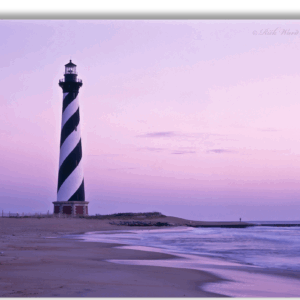 Photograph of Hatteras Lighthouse on the beach at sunset with purple skies.