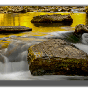 Photograph of Tellico River with golden autumn reflections and cascading water over rocks.